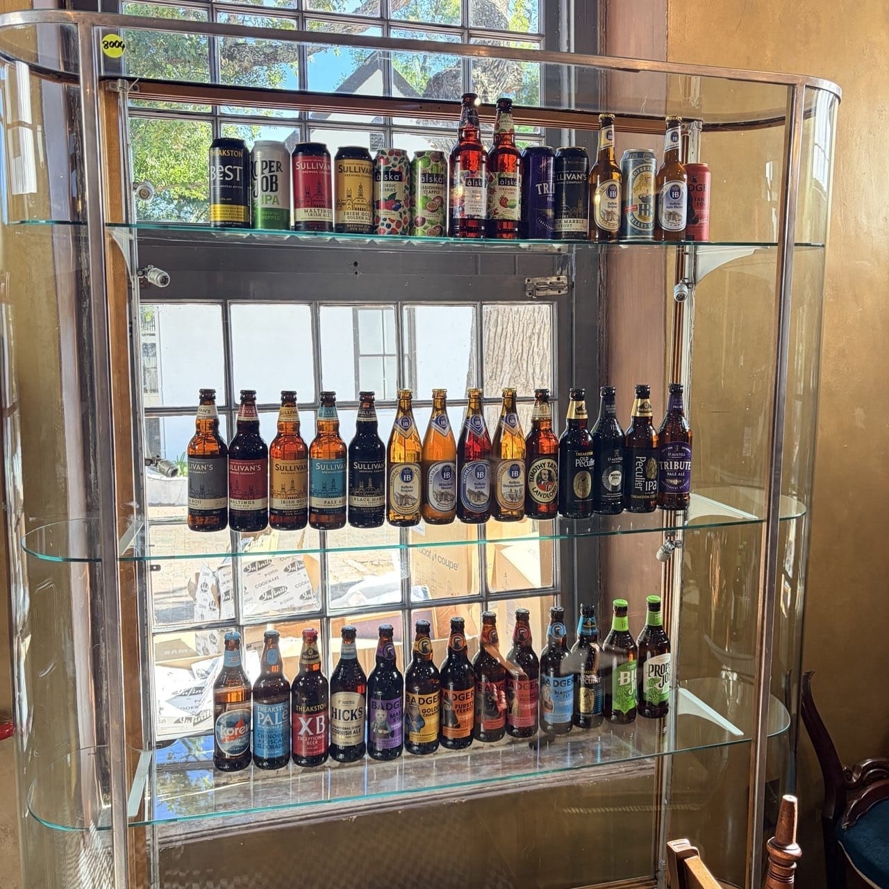 The bottle store display cabinet at Kronendal 1713 in Hout Bay, three glass shel The bottle store display cabinet at Kronendal 1713 in Hout Bay, three glass shelves of imported bottled beer and cans from Ireland, England, Germany and Sweden